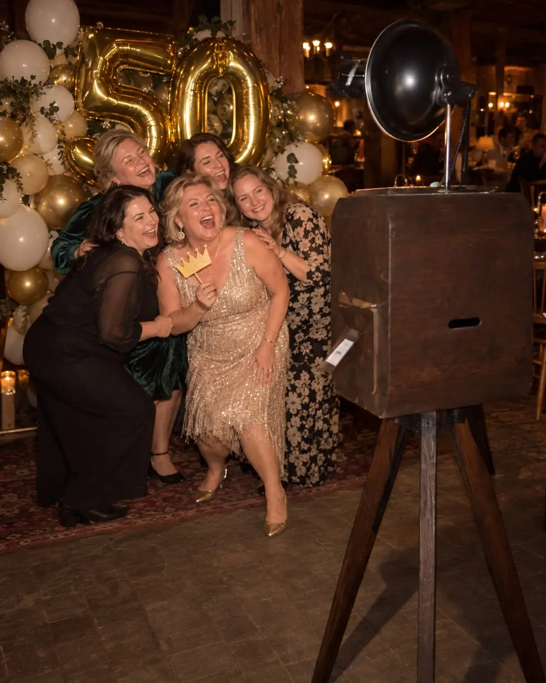 Jubilāre ar draudzenēm pozē foto kastei pie zelta baloniem 50