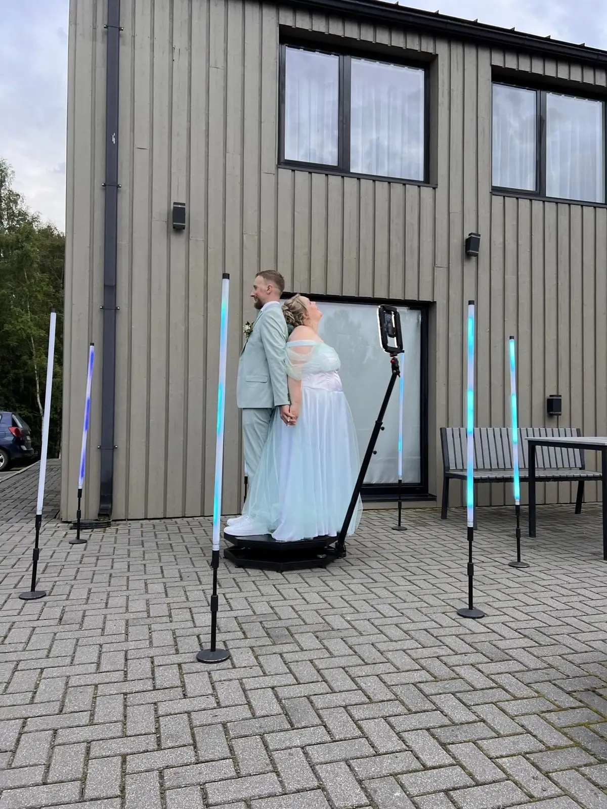 Jaunais pāris apskaujas uz 360 video spinera platformas brīvdabā starp LED gaismas stabiem