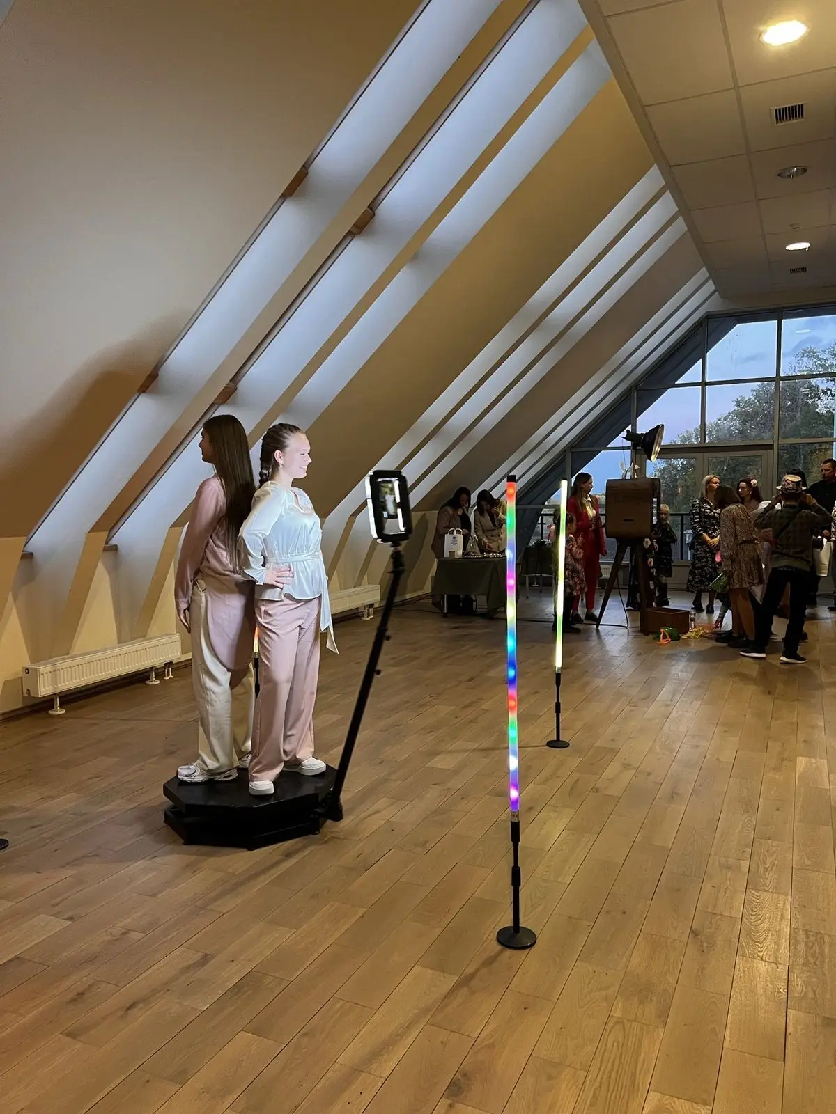 Divas viešņas pozē uz 360 video spinera platformas svētku zālē