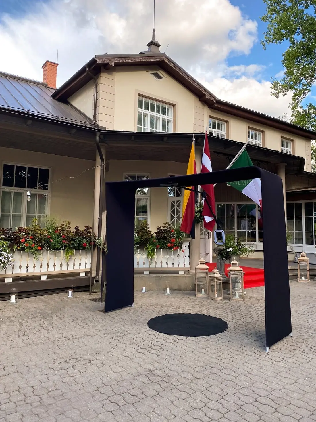 TOP 360 video spinera arka ar melnu paklāju muižas pagalmā pie ieejas ar karogiem